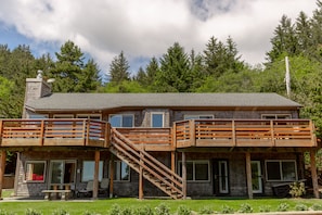 A two-story house with a deck, a staircase, and a covered patio area. - Headland- Oceanfront Family Friendly (Gold Beach)