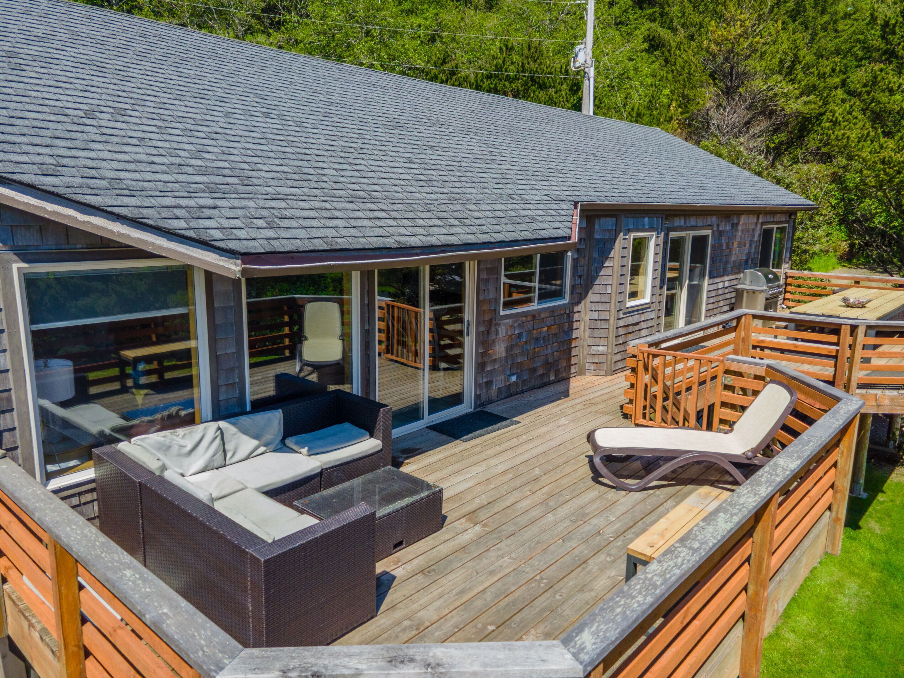 Une maison moderne dotée d’une terrasse, d’un espace salon extérieur et d’un coin barbecue.