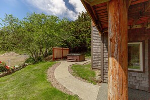 A backyard with a curved concrete path, a hot tub, and a wooden shed. - Headland- Oceanfront Family Friendly (Gold Beach)
