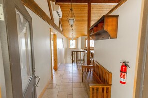 A hallway with wooden beams, a fire extinguisher, and a staircase. - Headland- Oceanfront Family Friendly (Gold Beach)