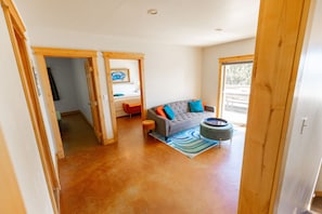 A spacious living area with a grey sofa, colorful cushions, a round coffee table, and a striped rug. - Headland- Oceanfront Family Friendly (Gold Beach)