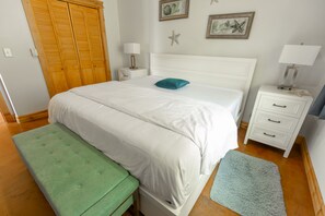 A neatly arranged bedroom with a bed, a green bench, a nightstand, and a dresser.