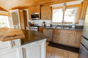 A kitchen with wooden cabinets, a microwave, a stove, and a sink. - Headland- Oceanfront Family Friendly (Gold Beach)