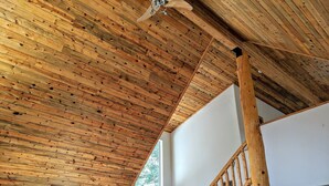 A wooden ceiling with a sloped design, a staircase with wooden railings, and a white wall with framed pictures and signs. - Relax with Family, Friends and Dogs, in a Secluded 4b/3b Cabin in the Woods (Fairplay)