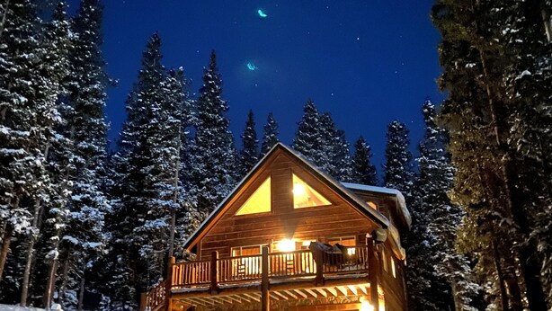 A cabin with a balcony, surrounded by snow-covered trees, under a starry night sky. - Relax with Family, Friends and Dogs, in a Secluded 4b/3b Cabin in the Woods (Fairplay)