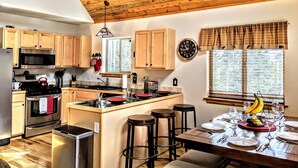 A kitchen with wooden cabinets, a stainless steel stove, a microwave, and a window with blinds. - Relax with Family, Friends and Dogs, in a Secluded 4b/3b Cabin in the Woods (Fairplay)