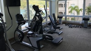 Un gimnàs amb màquines de cardio, pèses i una televisió penjada a la paret.