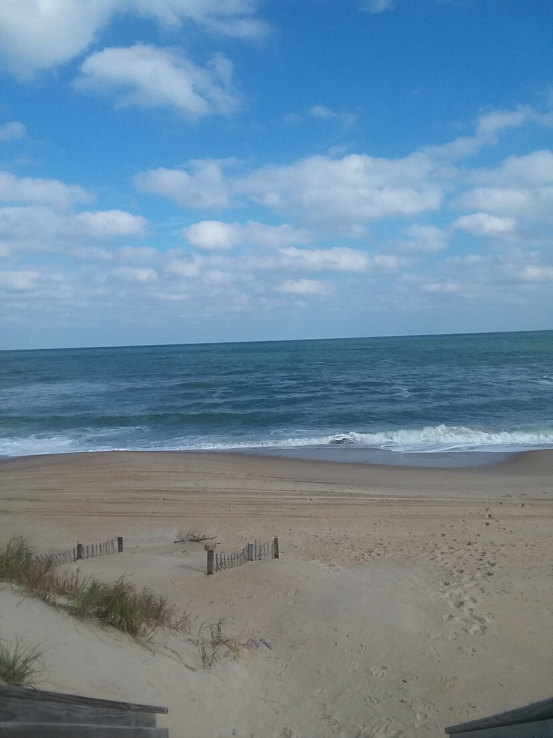 Ein Strand mit einer Holzlattenverkleidung und freiem Blick auf den Ozean.