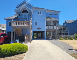 A two-story house with a front porch, a garage, and a driveway. - Village of Nags Head, Ocean side 3-minute walk to beach, Private Pool, Hot Tub (Nags Head)