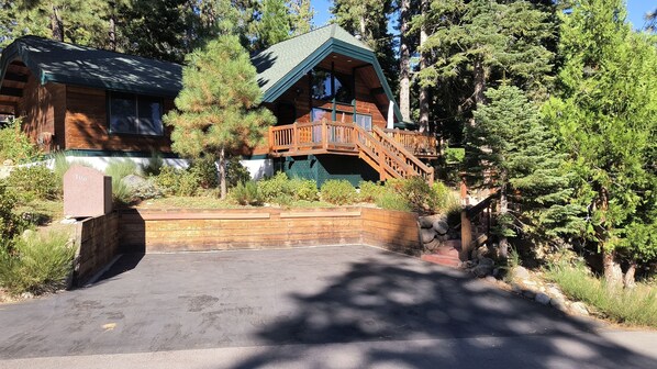 Surrounded by lush greenery and tall pine trees, this lodge features a green roof and brick exterior, blending seamlessly into its natural surroundings.