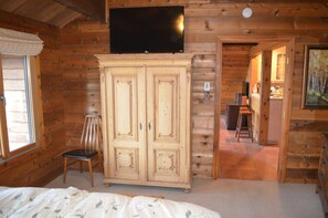 Cozy cabin-style room with a large wardrobe, flat-screen TV, and comfortable bed.