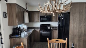 Eine moderne Küche mit Holzschränken, einem schwarzen Kühlschrank, einer Mikrowelle und einem Herd.