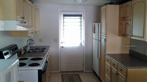 A compact kitchen with basic appliances, wooden cabinets, and a small window. - Heaven Can't Wait, On Beautiful Kinderhook Lake!! (Valatie)