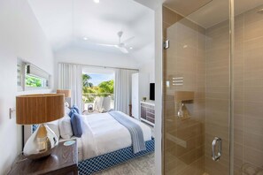 Relax in a spacious room with a large bed, walk-in shower, and a window offering a view of lush greenery.