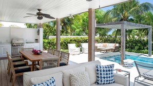 A covered outdoor area with a pool, a dining table with chairs, a sofa with patterned cushions, and a grill. - Second Chances: Spacious Villa w/Pool, Near Beach (Leeward Settlement)