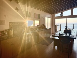 Eine Küche mit Meerblick, ein Essbereich mit Tisch und Stühlen sowie eine Küchenzeile mit diversen Gegenständen.
