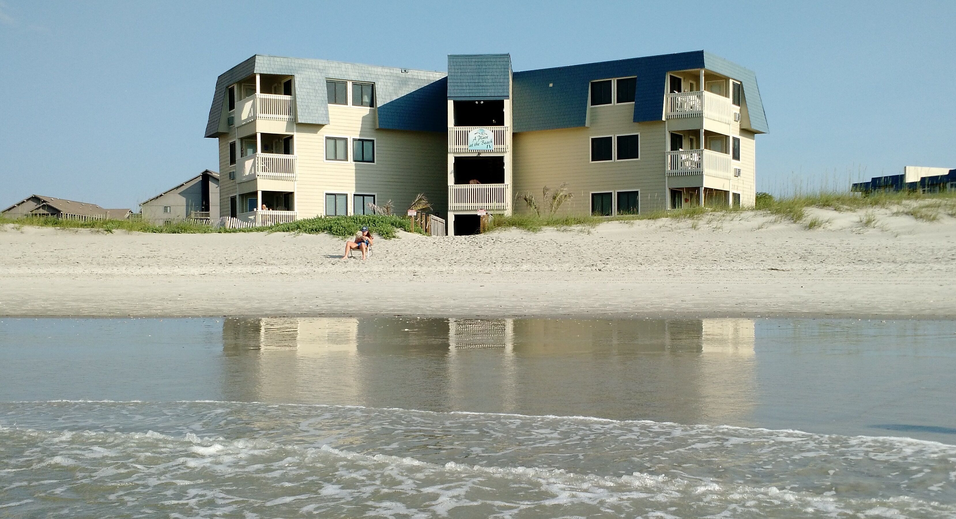 Een hotel met meerdere verdiepingen, balkons en uitzicht op het strand.