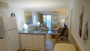 Cocina compacta con refrigerador, mesa de comedor y sofá.
