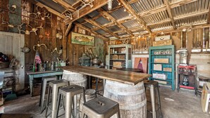 A rustic bar area with wooden barrels, stools, and a vintage counter. - The St. Helena House (Saint Helena)