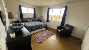 Une chambre à coucher avec un grand lit, une chaise, un bureau avec un bol et un tapis.