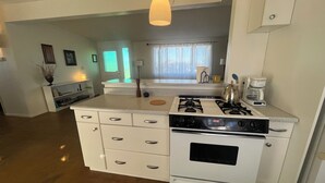 Une cuisine avec des meubles blancs, une cuisinière et une machine à café.