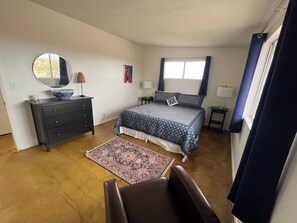 Een slaapkamer met een bed, een dressoir, een spiegel, nachtkastjes en een stoel.