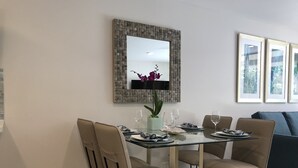 Een eetgedeelte met een glazen tafel, beige stoelen en een potorkidee.