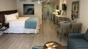 Een hotelkamer met een bed, een bureau, een zithoek en een keuken.