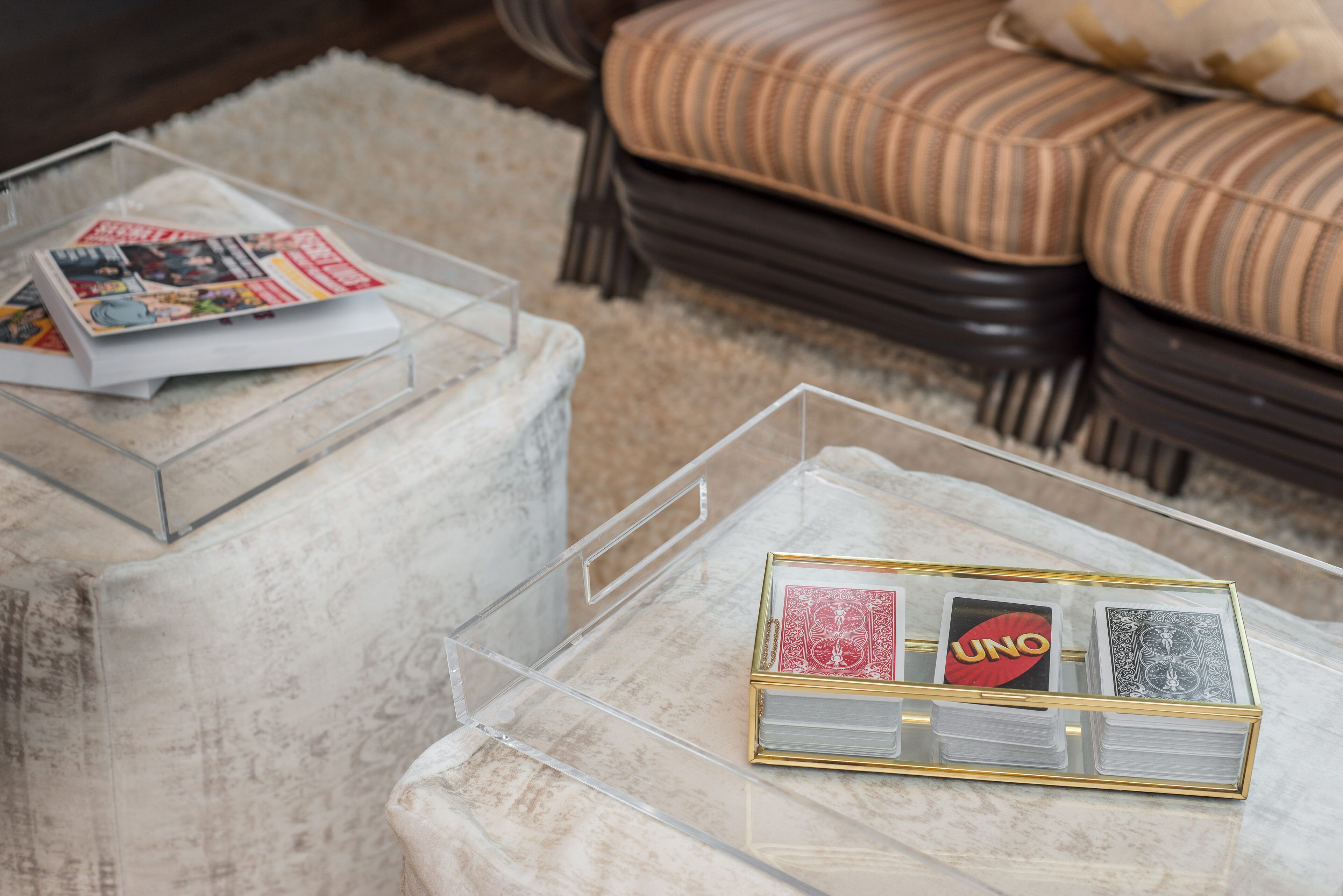 A clear glass coffee table with a stack of playing cards and a magazine.