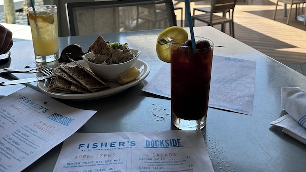 Speisekarte vom Restaurant Fisher's Dockside mit Blick auf den Hafen und Sonnenschirme.