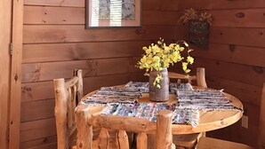 Ein Holzinterieur mit einem runden Tisch, Stühlen, einer Hängelampe und einem gerahmten Bild an der Wand.