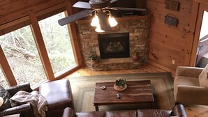 Ein gemütliches Blockhaus-Interieur mit Kamin aus Stein, Ledersofa und Holzboden.