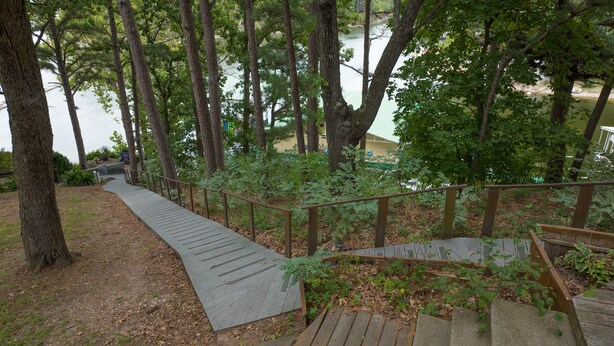 A wooden staircase leading down to a river, surrounded by trees and greenery.