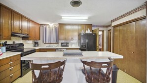 A kitchen with wooden cabinets, a black refrigerator, a microwave, a stove, and a dining table with chairs.