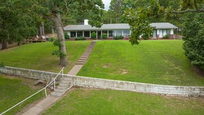 A house with a front porch, a stone retaining wall, and a well-maintained lawn.