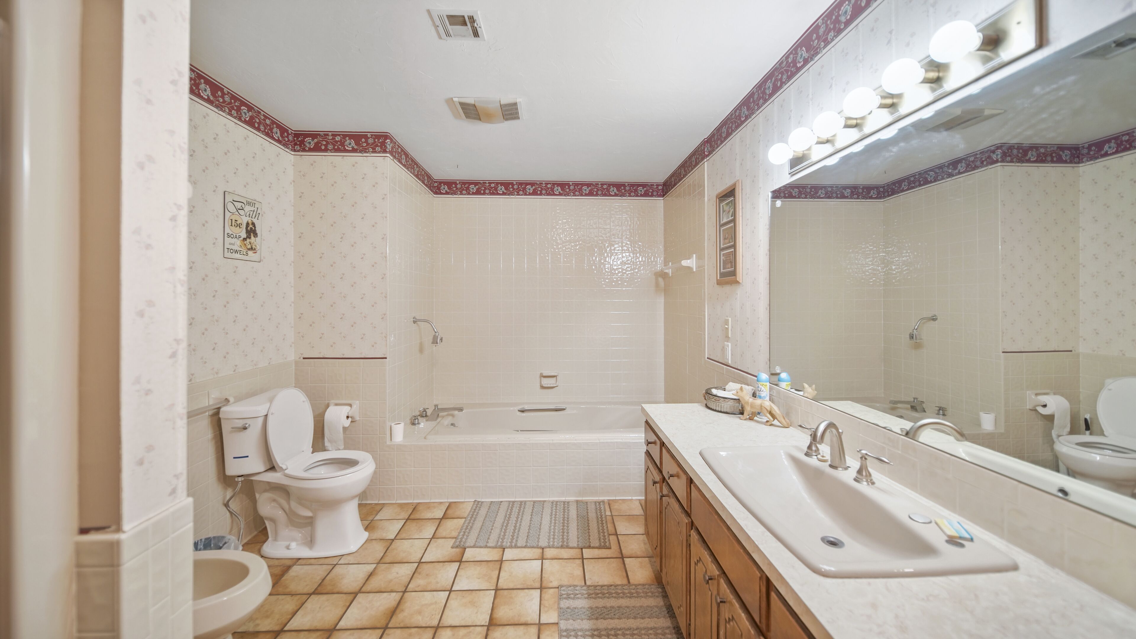 A bathroom with a toilet, sink, bathtub, and a large mirror.