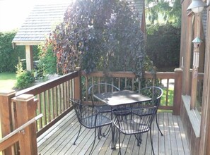 A wooden deck with a table and chairs, surrounded by a wooden railing. - Lake Whatcom Beach Resort (Bellingham)