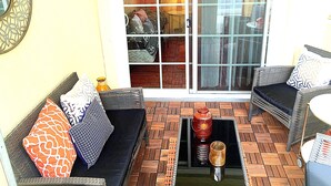 A sunlit patio with wicker furniture, a glass table, and a view through a sliding glass door. - Steps to the water on both sides!! Mango Tango (San Diego)