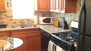 A kitchen with wooden cabinets, a microwave, a stove, and a refrigerator. - Steps to the water on both sides!! Mango Tango (San Diego)