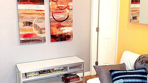A living room with a white sofa, a coffee table with books, and two abstract paintings on the wall. - Steps to the water on both sides!! Mango Tango (San Diego)