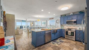 Een moderne keuken met blauwe kastjes, roestvrijstalen apparatuur en een groot eiland.