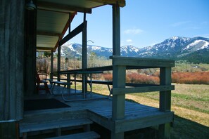 A wooden deck with picnic tables and chairs, overlooking a mountainous landscape. - Aspen Cabin Near Yellowstone - Horse Rides, Zip Lining, Rafting, Hiking (Gardiner)