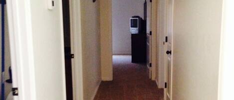 A narrow hallway with carpeted floors and white walls.