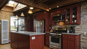 A kitchen with wooden cabinets, a central island, stainless steel appliances, and a stone accent wall.