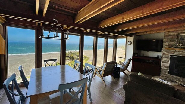 A spacious room with a large wooden table and chairs, a stone fireplace, and a television.