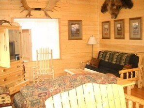 Cozy cabin interior with a rustic charm, featuring a sofa, wooden chair, and wooden dresser.