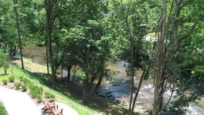 Une promenade au bord de la rivière, agrémentée de bancs, entourée d’arbres et traversée par un petit ruisseau.