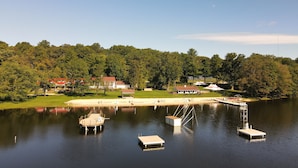 A lake with docks and a small boat, surrounded by trees and buildings. - Cozy Mount Gretna Chautauqua Cottage near Hershey with treehouse porch  (Mount Gretna)