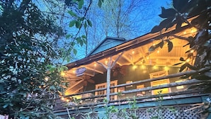 A wooden building with a balcony, surrounded by dense foliage. - Cozy Mount Gretna Chautauqua Cottage near Hershey with treehouse porch  (Mount Gretna)