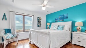 A bedroom with a bed, a chair, a nightstand, and a view of the beach. - 4BR/4Bth Direct Oceanfront,House,Covered Porch and fireplace! (Edisto Beach)